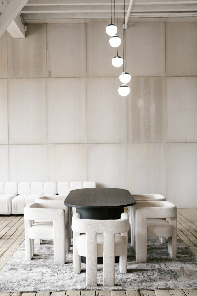 Grooms suite with a black tabel, white chairs and round ball chandelier