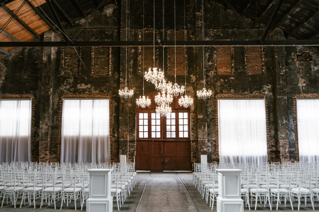 Ceremony location with red doors, white chairs, and vintage chandeliers