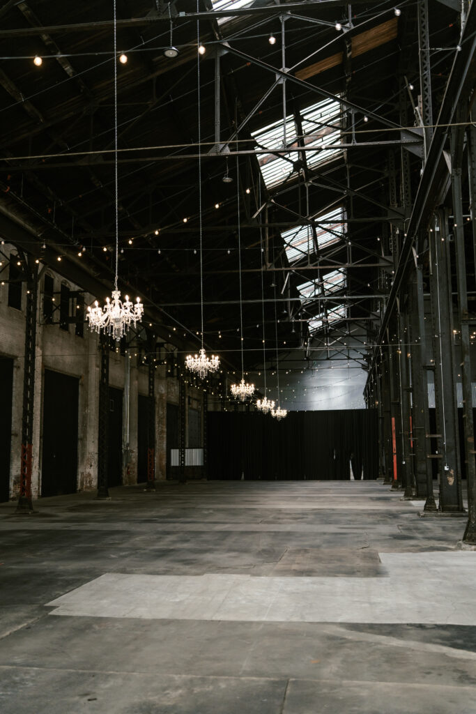 large area for a wedding reception with tall black ceilings and chandeliers