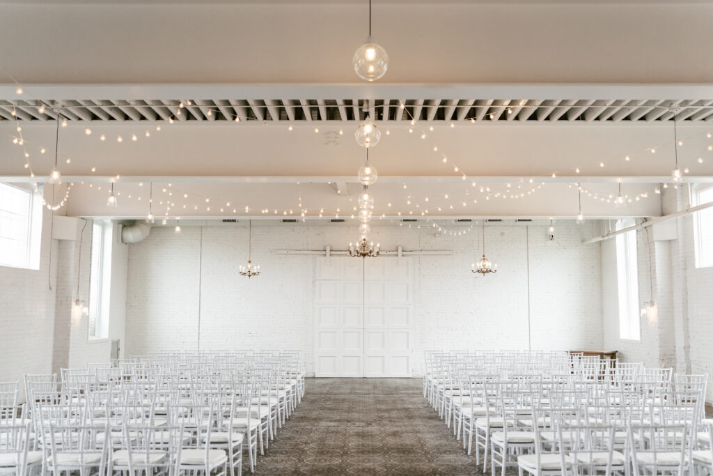 White room with string lights strung above white chairs